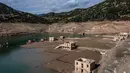 Foto ini menunjukkan sisa-sisa rumah yang muncul kembali ketika permukaan danau buatan Mornos menurun akibat kekeringan, di desa Kallio, sekitar 240 km barat laut Athena, Yunani pada 3 November 2025. Situasi ini memicu kekhawatiran akan potensi kekurangan air di kota tersebut. (Angelos TZORTZINIS/AFP)