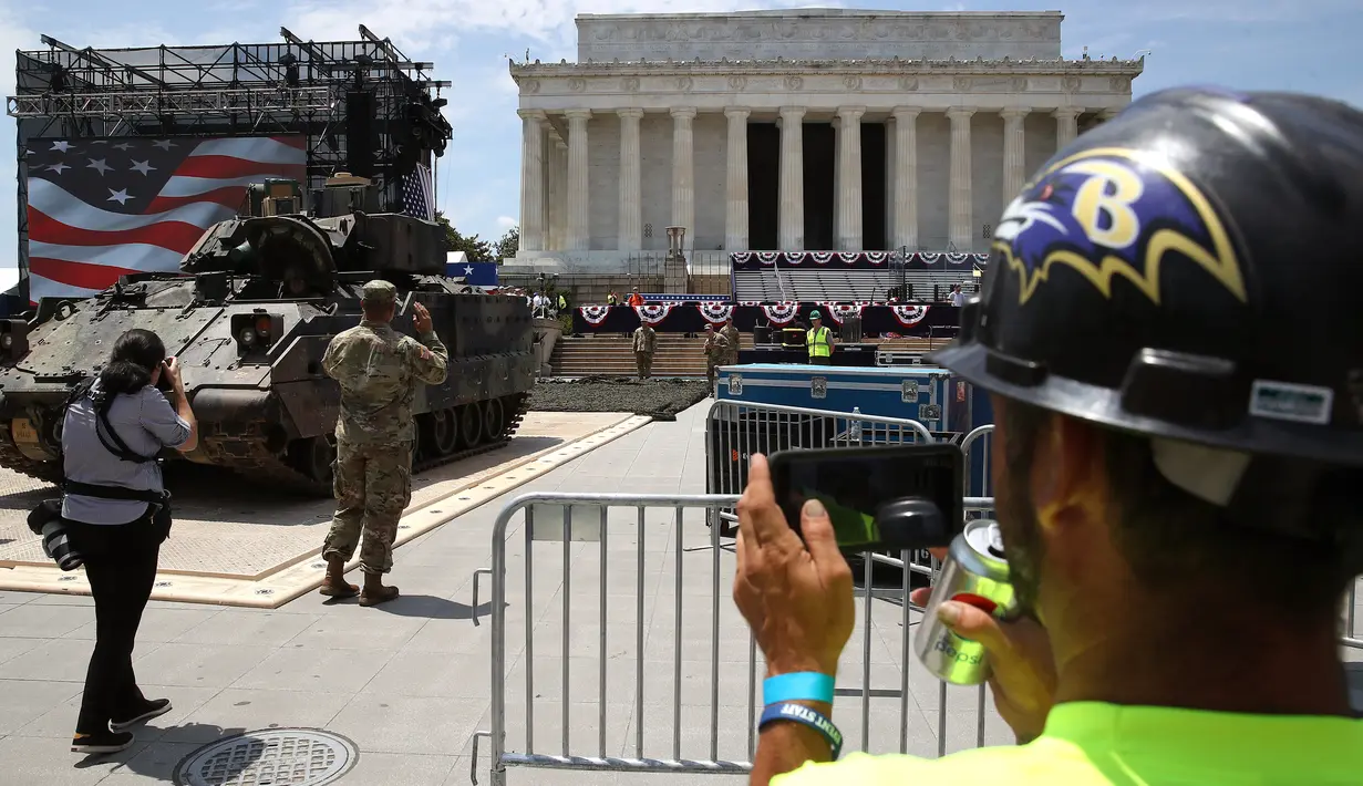 Pekerja mengambil gambar saat kendaraan pengangkut lapis baja Bradley dipindahkan di depan Lincoln Memorial, Washington, Rabu (3/7/2019). Donald Trump akan memamerkan tank-tank tempur sebagai bagian dari perayaan Hari Kemerdekaan AS yang dikenal sebagai Fourth of July. (Mark Wilson/Getty Images/AFP)