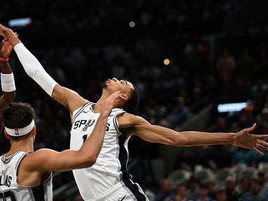 Pebasket San Antonio Spurs, Victor Wembanyama (kanan) berusaha merebut bola dari pebasket Dallas Mavericks pada laga pertama NBA musim 2023/2024 di AT&T Center in San Antonio, Texas, Kamis (27/10/2023). Ini merupakan laga perdana bagi Wembanyama di NBA. (AFP/Chandan Khanna)