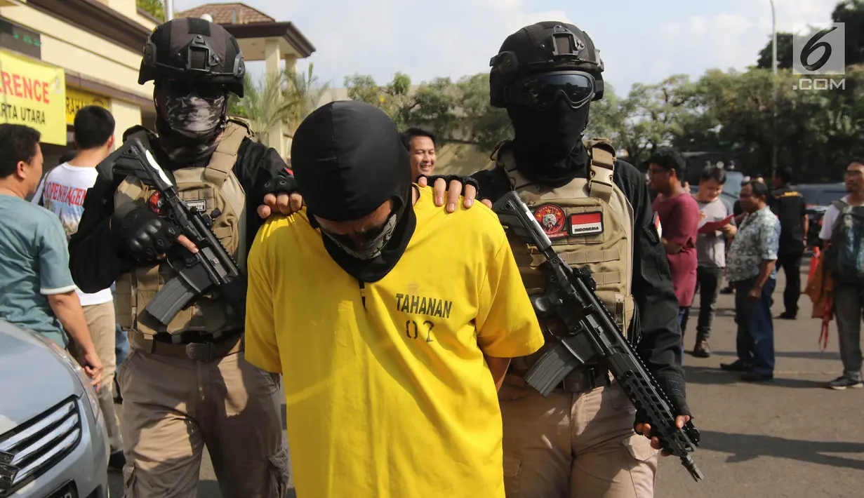 Petugas mengawal tersangka saat rilis di Polres Metro Jakarta Utara, Jumat (6/4). Petugas juga menyita 1 buah tangki air tempat alkohol, 2 buah jerigen berisi alkohol, label miras, dan bahan-bahan untuk pembuatan miras. (Liputan6.com/Arya Manggala)