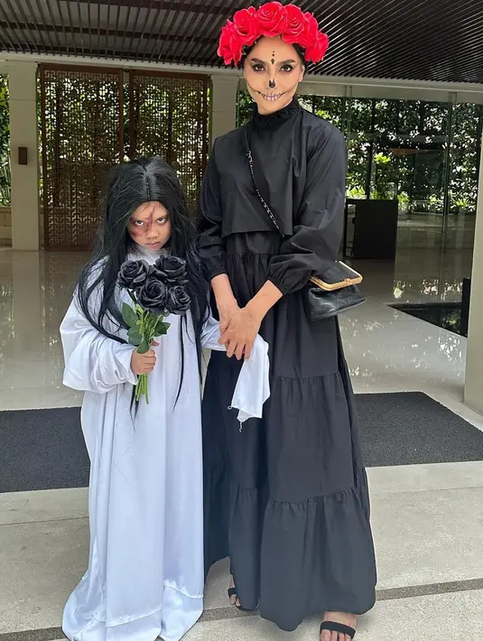 Ririn Ekawati tampil dengan dress hitam, mengenakan red rose flower headpiece dengan makeeup menyeramkan. Sedangkan, si kecil dengan kostum kuntilanaknya. [@ririnekawati]