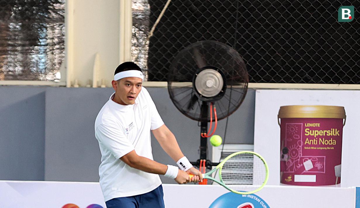 <p>Rezky Aditya berusaha mengembalikan bola dalam pertandingan tenis tunggal putra Turnamen Olahraga Selebriti Indonesia melawan Randy Pangalila yang berlangsung di Gelanggang Olahraga UNJ, Rawamangun, Jakarta Timur, Sabtu (29/7/2023). (Bola.com/Abdul Aziz)</p>