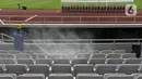 Petugas menyemprotkan cairan disinfektan ke kursi penonton di Stadion Utama Gelora Bung Karno (SUGBK), Jakarta, Kamis (26/3/2020). Penyemprotan dilakukan guna mencegah penyebaran virus corona COVID-19 di seluruh venue kawasan SUGBK. (merdeka.com/Imam Buhori)