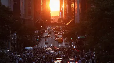 Matahari terbenam di Manhattan ketika fenomena "Manhattanhenge" di 42nd street, New York, Senin (11/7/2022). Manhattanhenge adalah keadaan dimana matahari terbenam tepat berada dalam garis lurus dengan jalanan Manhattan yang melintang dari timur ke barat. (Yuki IWAMURA / AFP)