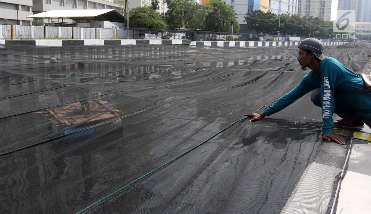 Petugas memasang jaring hitam di Kali Item, Kemayoran, Jakarta, Jumat (20/7). Pemasangan jaring tersebut merupakan cara Pemprov DKI mengatasi bau sebelum menerima atlet Asian Games 2018 yang akan menginap di Wisma Atlet. (Liputan6.com/Arya Manggala)