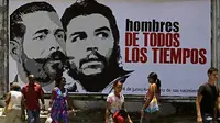 Warga berjalan disamping papan iklan dengan gambar pejuang kemerdekaan Kuba Antonio Maceo (kiri) dan pemimpin revolusi Che Guevara di Havana, Selasa (14/6).(Antara).