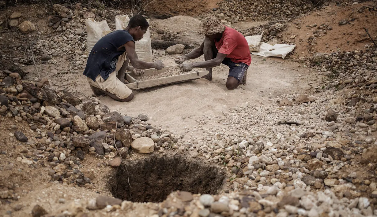Dua buruh tambang menyortir safir yang didapat di kawasan pertambangan Sakaraha, Madagaskar. Pulau yang terletak di Samudra Hindia itu sudah menjadi salah satu produsen tambang batu mulia safir terbesar di dunia. (AFP Photo/Gianluigi Guercia)
