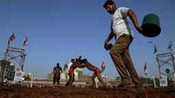 Panitia menyiram areal pertandingan Indian traditional wrestling competition atau Kushti di Arena Akhara, Mumbai, India, 20 Maret 2016.  Olahraga tradisional ini terus dilestarikan sebagai bagian dari budaya. (EPA/Divyakant Solanki)