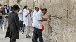 Pekerja pemeliharaan di Tembok Barat, situs paling suci di mana orang Yahudi diizinkan untuk berdoa, melakukan pembersihan untuk menghilangkan dari celah-celah pesan agama dan doa yang tertulis di selembar kertas yang ditinggalkan oleh ribuan jemaah sebelumnya, di kota tua Yerusalem pada 20 September 2022. (AFP/Ahmad Gharabli)