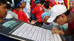 Seorang warga menandatangani dukungan deklarasi siber kreasi melawan hoax saat CFD di Jakarta, Minggu (5/11). Siber kreasi dibentuk dari berbagai komunitas dan elemen masyarakat. (Liputan6.com/Angga Yuniar)