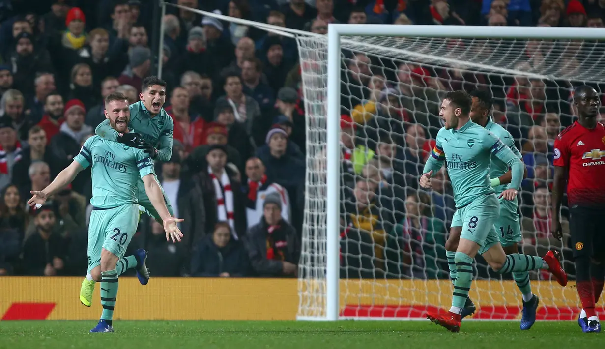 Bek Arsenal, Shkodran Mustafi (kiri) berselebrasi usai mencetak gol ke gawang Manchester United pada pertandingan lanjutan Liga Inggris di stadion Old Trafford (5/12). MU bermain imbang 2-2 atas Arsenal. (AP Photo/Dave Thompson)