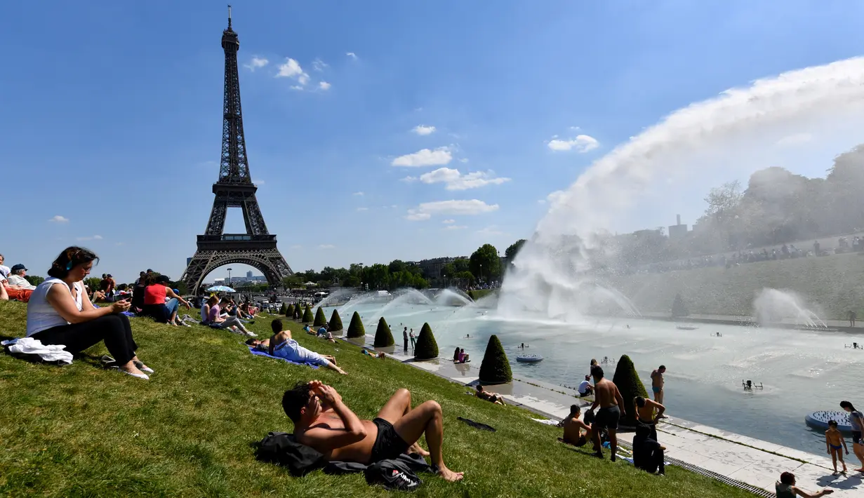 Warga berjemur di samping air mancur di Trocadero Esplanade, dekat Menara Eiffel, Paris (8/5). Kebun Trocadero Esplanade memiliki luas 93.930 meter persegi (23,21 hektar). (AFP Photo/Gerard Julien)