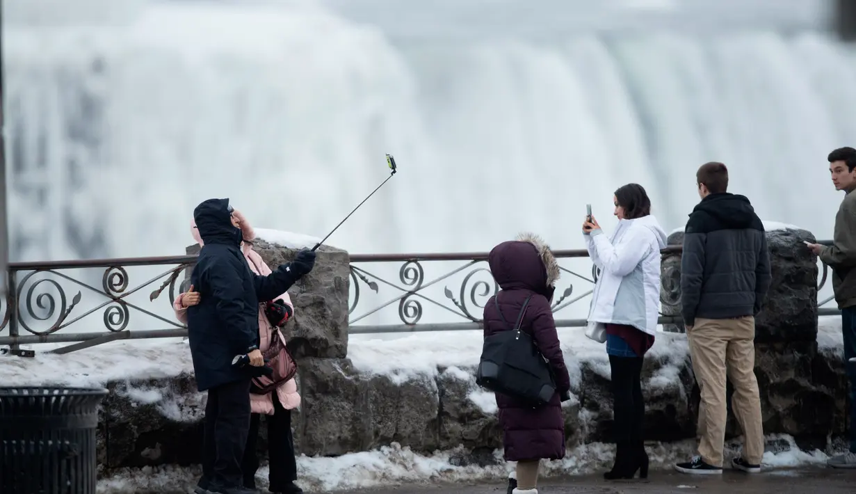<p>Sejumlah turis mengambil foto di depan Air Terjun Niagara, Ontario, Kanada, Senin (9/1). Air terjun Niagara adalah salah satu tempat wisata andalan Amerika Utara. (Geoff Robins/AFP)</p>