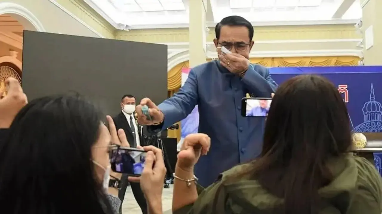 Perdana Menteri Thailand Prayuth Chan-ocha menyemprotkan cairan alkohol ke barisan depan wartawan yang duduk di dalam ruang konferensi pers di Government House di Bangkok, Thailand, Selasa, 9 Maret 2021.