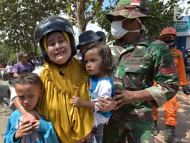 Anggota TNI mengavakuasi seorang wanita beserta kedua orang anak saat terjadi gempa susulan di Tanjung pulau Lombok, NTB, Kamis (9/8).Gempa susulan terjadi kembali dengan kekuatan 6,2 skala richter dikawasan tersebut.(AFP/ ADEK BERRY)