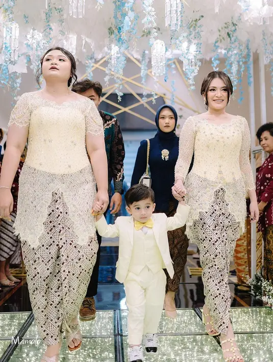 Mantan istri komedian Sule ini menggandeng Adzam yang tampil menggemaskan dengan setelan jas kuning. Warna kuning lembut yang dipilih Nathalie memberikan kesan ceria namun tetap berkelas, seolah menggambarkan suasana bahagia dalam acara pernikahan tersebut. Sepatu hak tinggi berwarna nude juga menyempurnakan gaya keseluruhannya. (Liputan6.com/IG/@nadyaholscher)