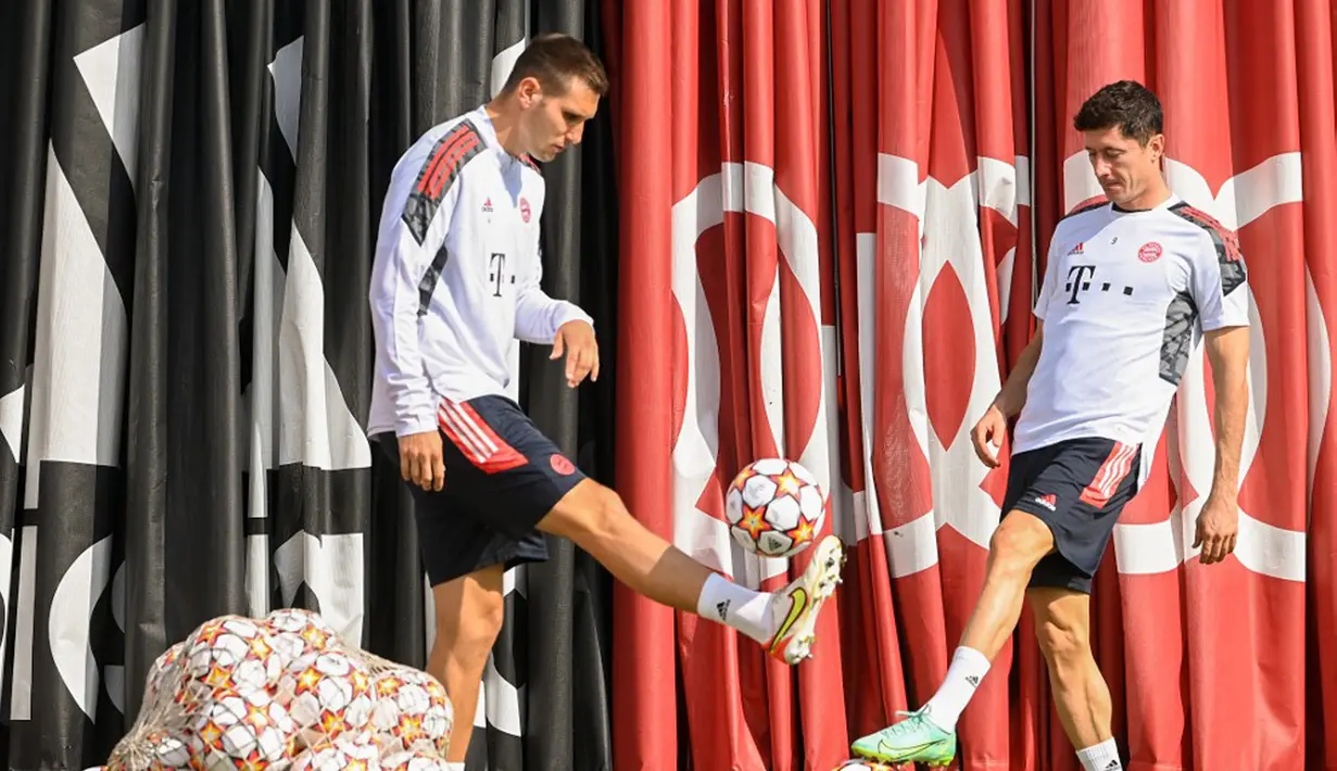 Pemain Bayern Munchen Niklas Suele (kiri) dan Robert Lewandowski (kanan) menendang bola saat sesi latihan di tempat latihan klub di Munchen, Jerman, 13 September 2021. Bayern Munchen akan menghadapi Barcelona pada pertandingan Grup E Liga Champions. (CHRISTOF STACHE/AFP)