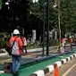 Petugas Suku Dinas PE Jakarta Pusat bersama Satgas PJU, mencabut dan menggeser tiang listrik dan lampu penerangan jalan yang menghalangi jalur sepeda di trotoar Jalan Asia Afrika dan Jalan Gelora, Senayan, Jakarta, Rabu (1/8). (Liputan6.com/Johan Tallo)