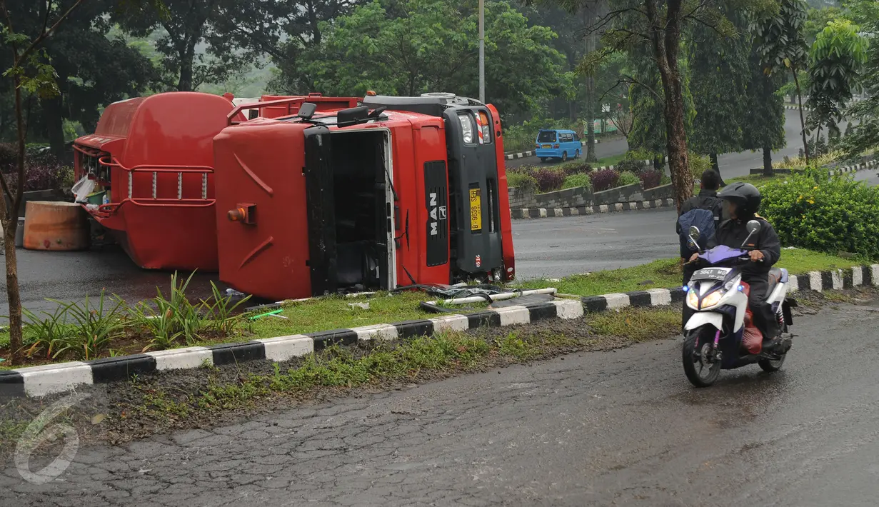Warga melihat kondisi truk tangki BBM yang terbalik di ruas Jalan Tegar Beriman Kabupaten Bogor, Jumat (15/4/2016). Truk tangki yang terbalik dalam kondisi penuh muatan BBM jenis premium. (Liputan6.com/Helmi Fithriansyah)