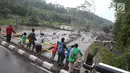Warga berdiri di jembatan menyaksikan aliran lahar dingin yang melintasi Sungai Yeh Sah di Karangasem, Bali, Sabtu (2/12). Banjir lahar dingin ini juga mengundang pengendara yang melintas untuk berfoto dan melihat-lihat. (Liputan6.com/Immanuel Antonius)