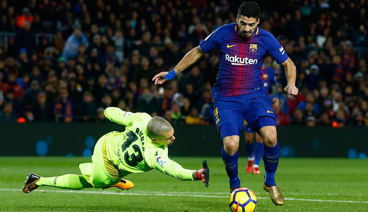 Pemain Barcelona, Luis Suarez berusaha menghindari kiper Deportivo La Coruna, Ruben Martinez pada pertandingan pekan ke-16 La Liga di Stadion Camp Nou, Senin (18/12). Barcelona unggul 4-0 tamunya La Coruna lewat dua gol Suarez. (AP/Manu Fernandez)