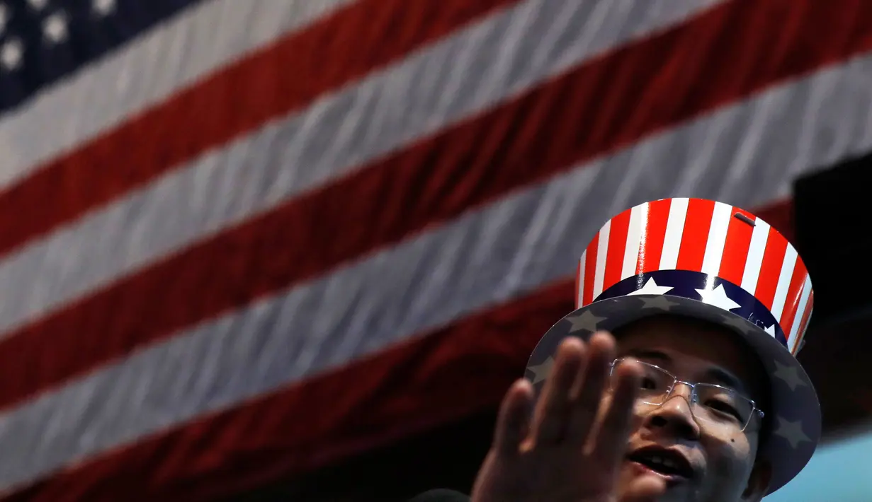 Seorang pria mengenakan topi bermotif bendera Amerika Serikat saat menonton siaran langsung pemilihan presiden AS yang digelar di Kedutaan Besar AS di Beijing, Rabu (9/11). (AP Photo / Andy Wong)