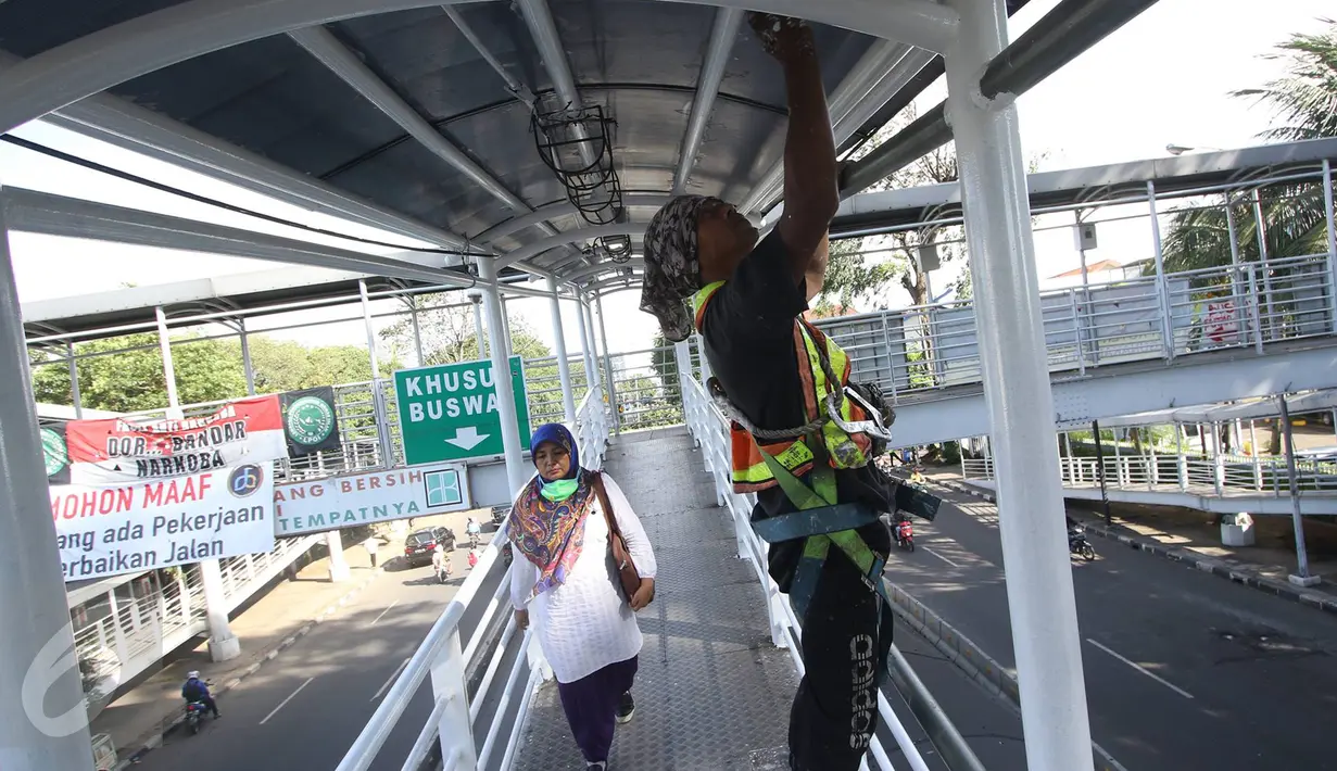 Pekerja menyelesaikan proses pengecatan jembatan penyeberangan menuju halte Transjakarta di kawasan Cawang, Jakarta, Rabu (5/4). Pengecatan dilakukan dalam rangka peremajaan halte yang rutin dilaksanakan. (Liputan6.com/Immanuel Antonius)