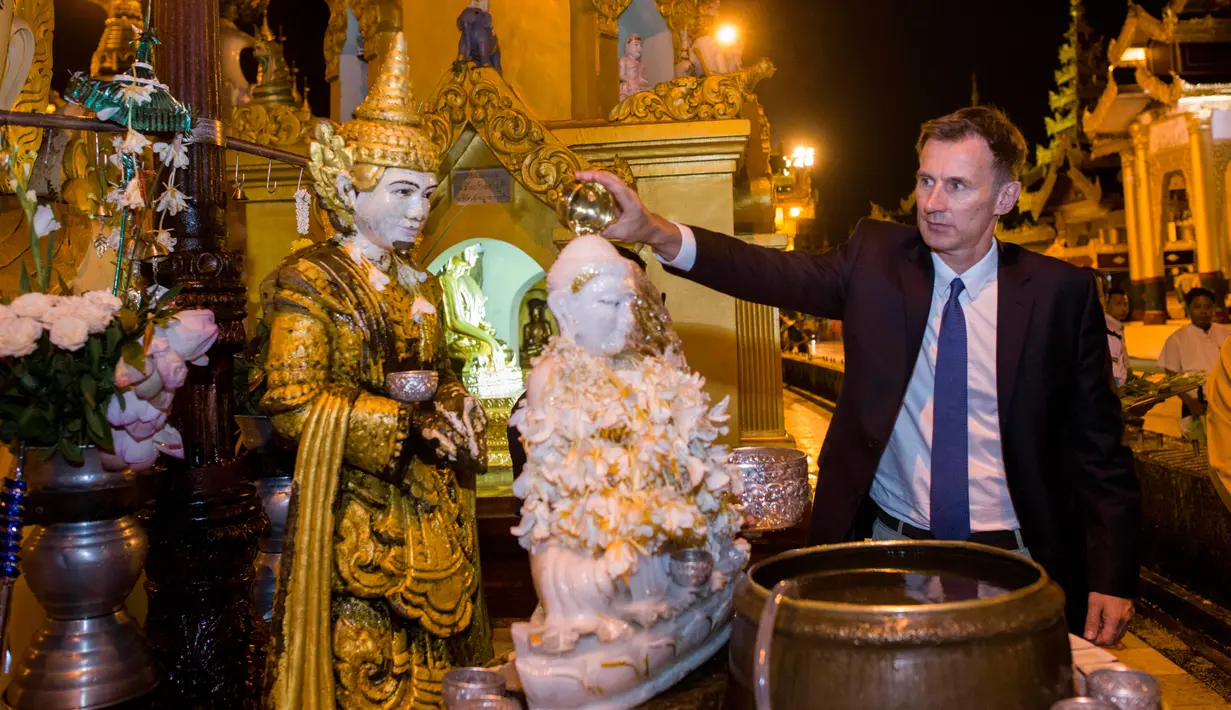 Menteri Luar Negeri Inggris, Jeremy Hunt menuangkan air ke patung Buddha ketika mengunjungi Pagoda Shwedagon di Yangon, Myanmar. Rabu (19/9). Hunt tiba di Myanmar untuk mengunjungi pusat krisis Rohingya dan menemui Aung San Suu Kyi. (AP/ Ye Aung Thu)
