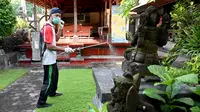Seorang petugas kesehatan menyemprotkan disinfektan di kawasan wisata di Sanur, Bali, Senin (16/3/2020). Penyemprotan dilakukan sebagai salah satu langkah untuk mengantisipasi potensi penyebaran virus Corona COVID-19 di kawasan pariwisata tersebut. (SONNY TUMBELAKA/AFP)