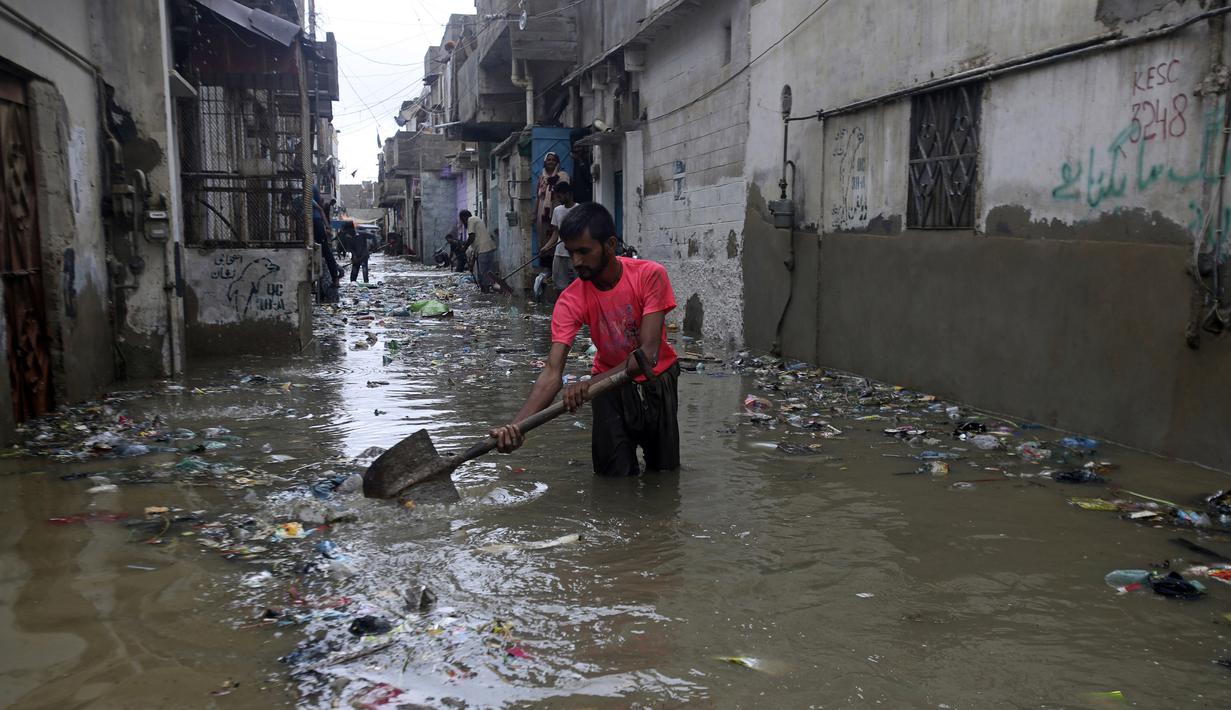 Seorang pria membersihkan jalan yang banjir setelah hujan deras, di Karachi, Pakistan, Selasa (30/7/2019). Departemen Meteorologi Pakistan mengatakan bahwa hujan memasuki provinsi Sindh dari Rajasthan India dan memperkirakan hujan akan turun tiga hari lagi. (AP Photo/Fareed Khan)