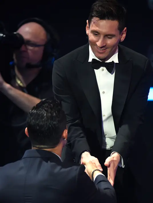Pemain Barcelona, Lionel Messi (kanan) berjabat tangan dengan pemain Real Madrid, Cristiano Ronaldo sebelum naik ke podium usai dinobatkan sebagai pemain terbaik dunia FIFA Ballon d'Or 2015 di Kongresshaus, Zurich, Senin ( 11/1). (AFP PHOTO/OLIVIER MORIN)