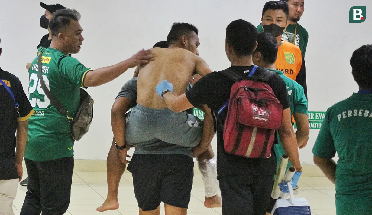 Bahkan Irfan Jaya sampai harus digendong ofisial Bali United untuk kembali ke kamar ganti. Ini merupakan langkah antisipasi agar cederanya tak semakin fatal. (Bola.com/Wahyu Pratama)