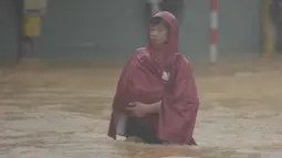 Seorang pria mengarungi jalan yang terendam banjir di Hue, Vietnam, Selasa, 28 Oktober 2025. Kementerian Lingkungan Hidup Vietnam pada Selasa (28/10/2025) mengatakan, tiga stasiun pengamatan di Kota Hue mencatat curah hujan antara 1.000 hingga 1.700 milimeter dalam periode 24 jam dari Minggu (26/10) hingga Senin (27/10/2025). (Van Dung/VNA via AP)