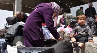 Seorang anak duduk di dekat ibunya saat sampai di sebuah tempat penampungan sementara di Jibrin di pinggiran timur Aleppo, Jumat (21/4). Pengungsi adalah warga dari kota Fuaa dan Kafraya. (AFP PHOTO / George OURFALIAN)