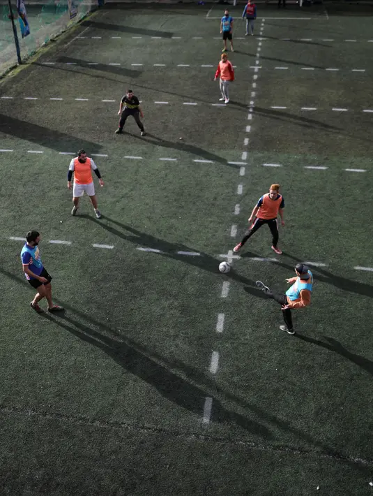 Sejumlah pria bermain sepak bola di klub lokal, Play Futbol 5, di Pergamino, Argentina, 1 Juli 2020. Demi bisa bermain di tengah pandemi Covid-19, klub membagi lapangan menjadi 12 persegi panjang untuk menandai area terbatas untuk setiap pemain, menjaga melakukan kontak fisik. (AP/Natacha Pisarenko)