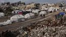 Sebagai informasi, menurut catatan Kementerian Kesehatan di Gaza hingga 27 Desember 2025, serangan Israel di Gaza telah menewaskan lebih dari 71.266 orang dan melukai lebih dari 171.200 lainnya. Serangan Israel di Gaza juga menghancurkan infrastruktur sipil dan melumpuhkan sistem layanan dasar. Tampak dalam foto, warga Palestina berjalan di sepanjang jalan melewati perkemahan tenda yang dikelilingi bangunan-bangunan yang hancur akibat serangan udara dan darat Israel di lingkungan Sheikh Radwan, Kota Gaza, Selasa, 30 Desember 2025. (AP Photo/Abdel Kareem Hana)