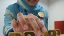 Petugas menunjukan emas batangan di Jakarta, Rabu (13/7). Harga buyback emas batangan dibuka turun di Rp 8.000/gram. (Liputan6.com/Angga Yuniar)