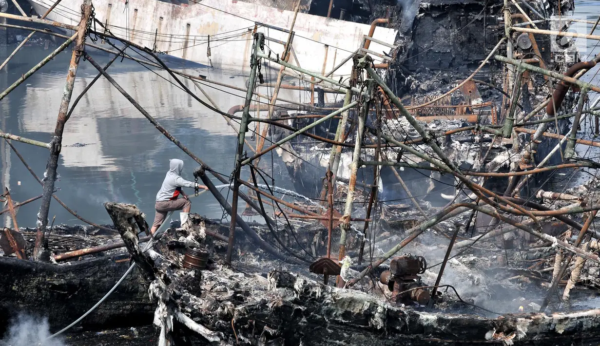 Seorang pria melakukan pendinginan kapal yang ludes dilalap api di Pelabuhan Muara Baru, Jakarta, Minggu (24/2). Belum diketahui mengenai taksiran kerugian materil akibat kebakaran tersebut. (Merdeka.com/Iqbal Nugroho)