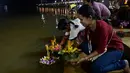 Orang-orang menghanyutkan 'krathong' untuk menandai festival Loy Krathong di sebuah danau di Narathiwat, Thailand,  Senin (11/11/2019). Festival ini biasanya berlangsung pada akhir musim hujan ketika bulan purnama menyala di langit pada November. (Madaree TOHLALA / AFP)