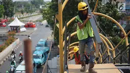 Pekerja menyelesaikan pembangunan Jembatan Penyebaran Orang (JPO) Pasar Minggu di Jakarta Selatan, Kamis (26/9/2019). JPO berdesain artistik senilai Rp 7 miliar tersebut ditargetkan rampung pengerjaannya pada Desember 2019 mendatang. (Liputan6.com/Immanuel Antonius)