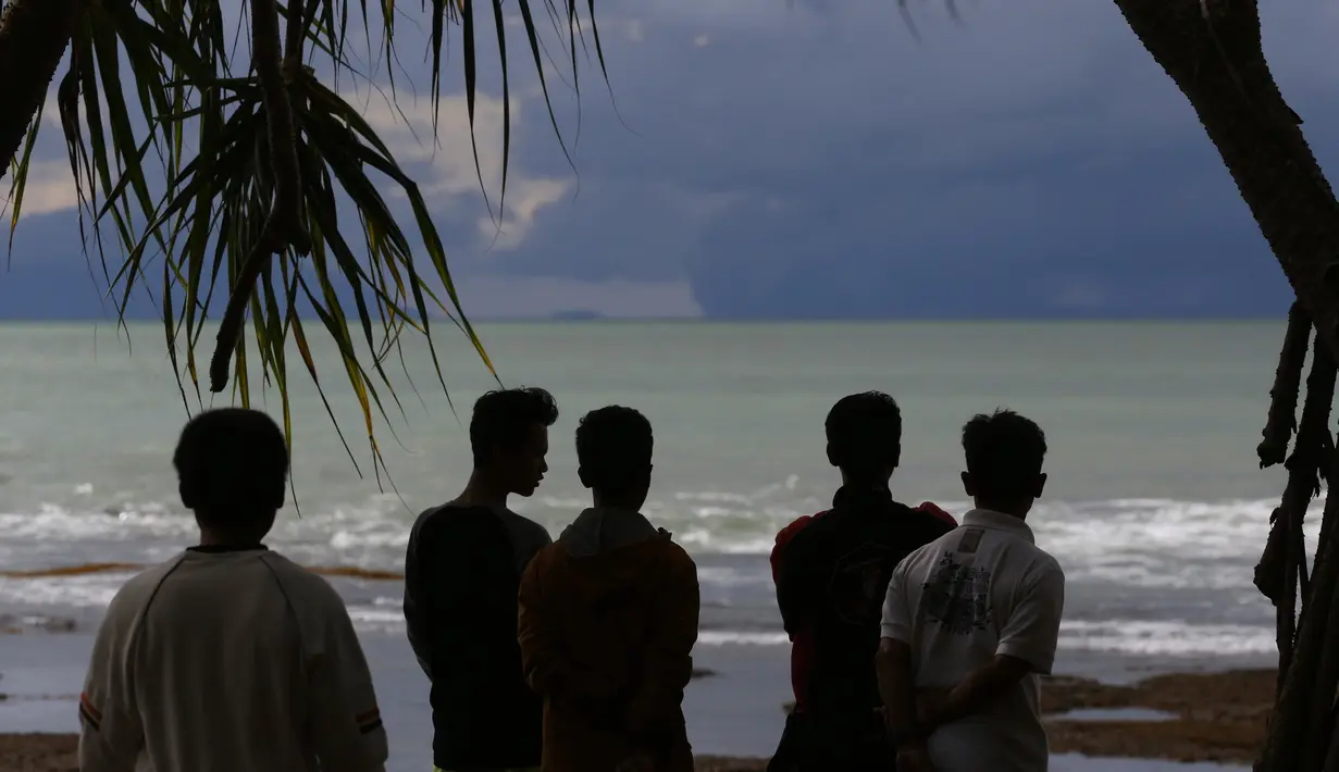 Warga melihat Gunung Krakatau (kiri) dan Anak Krakatau  di lepas pantai Carita, Banten (26/12). Pemerintah meminta warga menghindari pantai di daerah-daerah tersebut di mana tsunami telah menewaskan 420 jiwa akhir pekan lalu. (AP Photo/Achmad Ibrahim)