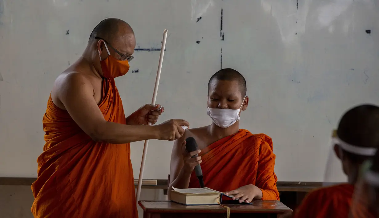 Biksu senior menyemprot mikrofon dengan disinfektan saat biksu muda belajar agama di Molilokayaram Educational Institute, Bangkok, Thailand, Rabu (15/4/2020). Sekitar 200 biksu muda tetap bersekolah kendati Thailand menutup semua sekolah selama lockdown akibat COVID-19. (AP Photo/Gemunu Amarasinghe)