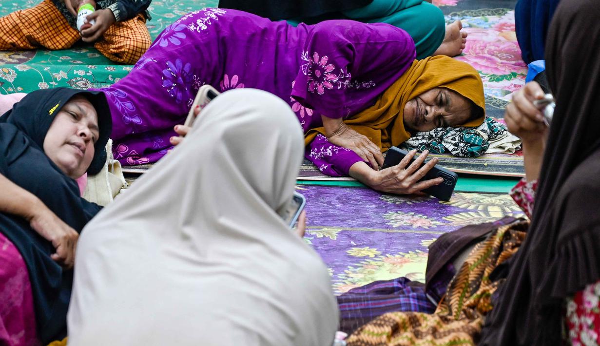 Untuk penanganan awal, Pemkab setempat telah membuka 17 lokasi pengungsian di Kecamatan Meureudu. Tampak dalam foto, warga desa terdampak banjir beristirahat di tempat pengungsian setelah banjir bandang melanda Meureudu, Kabupaten Pidie Jaya, Provinsi Aceh, pada 29 November 2025. (CHAIDEER MAHYUDDIN/AFP)