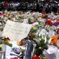 Sejumlah orang berdiri di balik pembatas tumpukan bunga di dekat Kafe Lindt, Sidney, Australia (16/12/2014). (REUTERS/David Gray)