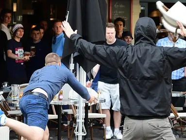 Seorang suporter Rusia melempar kursi ke arah fans Inggris saat bentrok antara kedua kubu di Lille, Prancis, Selasa (14/6/2016) atau Rabu dini hari WIB. (AFP/Leon Neal)