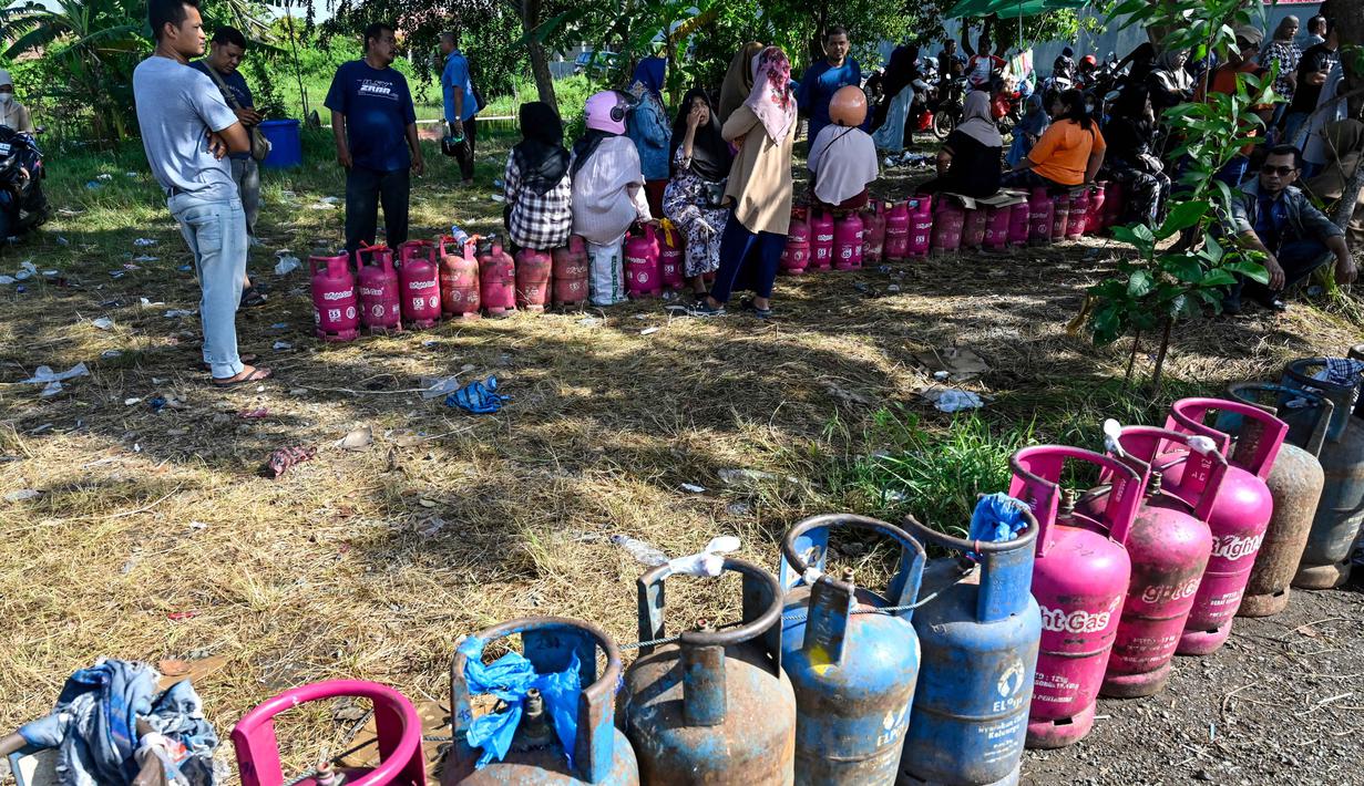 Di sisi lain, PT Pertamina (Persero) menyatakan telah menggunakan semua moda transportasi darat, udara, dan laut untuk memastikan distribusi energi, termasuk gas elpiji berjalan lancer. Tampak dalam foto, warga menunggu untuk membeli tabung gas di sebuah stasiun pengisian dan pembelian LPG setelah banjir bandang di Banda Aceh pada Rabu 17 Desember 2025. (CHAIDEER MAHYUDDIN/AFP)