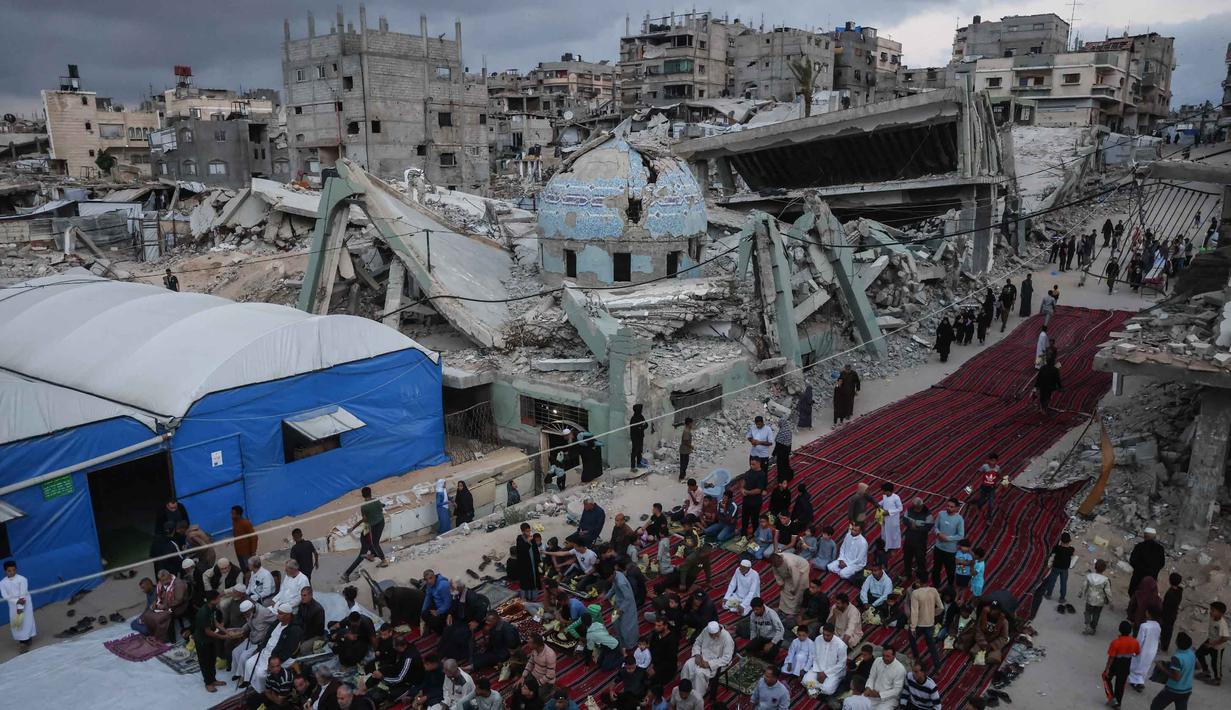 Warga Palestina berkumpul di jalan yang rusak parah untuk melaksanakan salat menandai dimulainya Idul Adha, Hari Raya Kurban, di Khan Yunis, Jalur Gaza Selatan, pada Rabu 27 Mei 2026. (BASHAR TALEB/AFP)