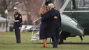 Presiden AS Donald Trump merangkul Melania Trump yang hampir terjatuh saat berjalan menuju helikopter kepresidenan di Gedung Putih, Senin (19/3). Melania Trump kehilangan keseimbangan saat mengenakan sepatu berhak 10 cm itu.  (AP/Pablo Martinez Monsivais)