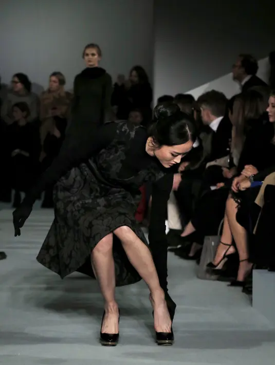 Seorang model berusaha memakai kembali sepatunya yang tak sengaja terlepas ketika memperagakan koleksi Oscar de la Renta Fall/Winter 2016 pada pagelaran New York Fashion Week di New York, Selasa (16/2/2016). (REUTERS/Brendan McDermid)