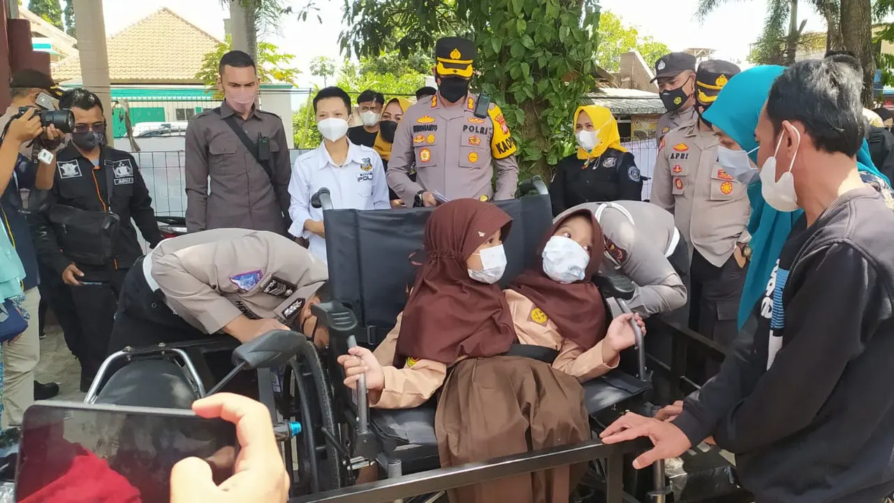 Kapolres Garut AKBP Wirdhanto Hadicaksono memberikan bantuan kursi roda khusus bagi Ai Putri Anugrah (8) dan Ai Dewi Putri Ningsih (8), anak kembar siam siswi kelas 2 di SDN 1 Tegalpanjang, Kecamatan Sucinaraja, Garut, Jawa Barat.